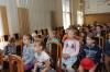 Dzieci siedzą na krzesłach w sali konferencyjnej i słuchają wykładu o wrocławskim Archiwum.