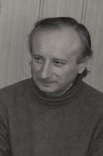 Czarno-biała fotografia mężczyzny w średnim wieku, ubranego w ciemny sweter.