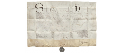 Lekko pogięty, stary, średniowieczny dokument pergaminowy pisany odręcznie z pieczęcią. U góry ozdobne duże litery dokumentu.