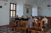 Czterech mężczyzn i pięć kobiet siedzą na sali wystawowej w starym budynku z łukowymi sklepieniami i słuchają wykładu.