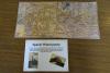 Brązowy stół, na którym leży mapa oraz kartka z napisem "Spacer Historyczny". Na mapie wytyczona jest trasa spaceru.